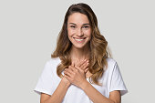 Head shot portrait grateful young woman holding hands on chest