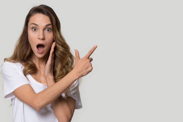 istock Surprised excited young woman pointing finger at copy space 1215784447