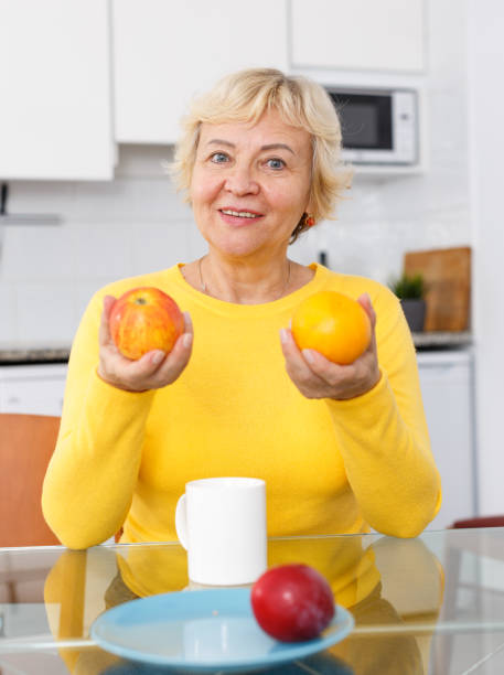 istock Senior lady at kitchen table fruits 1215786229