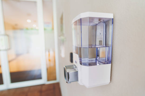 un desinfectante de manos de uso público unido a la pared fuera de la puerta principal de un edificio. - hand sanitizer liquid soap hygiene healthy lifestyle fotografías e imágenes de stock