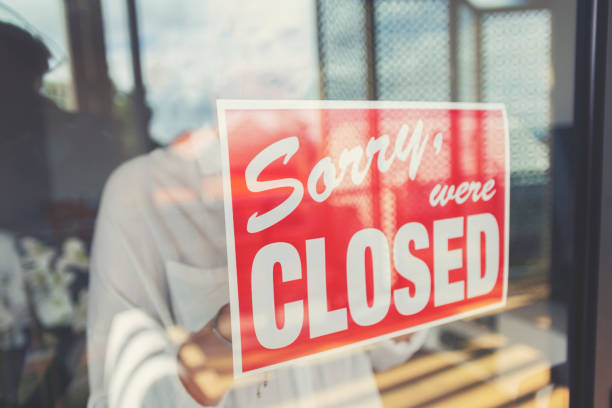 store owner putting up a closed sign in the window. - business closed imagens e fotografias de stock