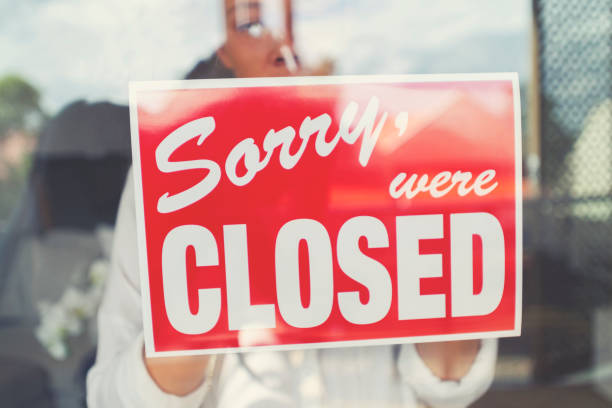 istock Store owner putting up a closed sign in the window. 1215786334