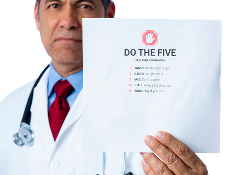 Doctor showing a paper with the five things we should do to help stop cover-19 that if you follow the five guidelines on the paper we can help stop the Covid-19 coronavirus. White background.