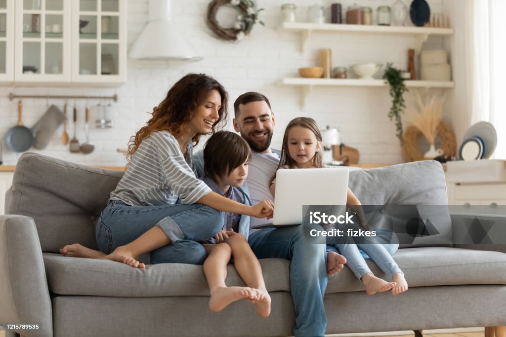 De gelukkige familie met jonge geitjes zit op laag gebruikend laptop - Royalty-free Familie Stockfoto