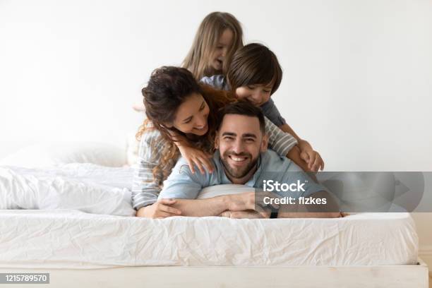 Happy Young Family With Kids Relax In Bedroom Stock Photo - Download Image Now - Family, Mattress, Bed - Furniture