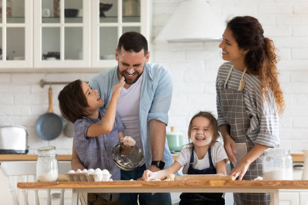 genitori felici con bambini piccoli si divertono a cucinare in cucina - home baking foto e immagini stock