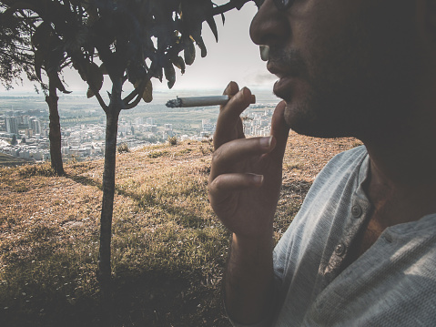 A young man smokes in the forest.