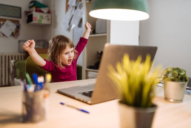 istock Ecstatic three year old girl celebrating winning on video game on laptop 1215792115