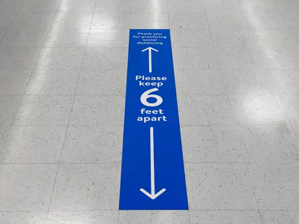 Photo of Social distancing floor sign warning about safe distance between people of 6 feet. Public health measure to prevent further spread of new corona virus Covid-19 infections.
