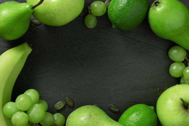 Flat lay top view. Summer abstract creative trendy fresh concept. Green fruits background. Dark stone slake plate with copy space.