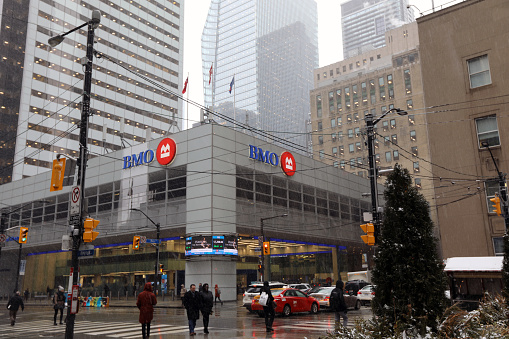 February 26, 2020 - Toronto, Ontario, Canada: Financial District of Toronto - Bay and King Street intersection, and BMO Bank building. BMO bank in downtown Toronto on Bay Street with pedestrians, cars and taxi on a snowy day in February 2020. Finance and banking industry in Canada. Canadian bank. Canadian economy