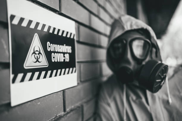 istock Man with protective suit standing next to the Coronavirus warning sign 1215803982