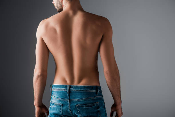 back view of sexy shirtless man in jeans on grey - shirtless imagens e fotografias de stock