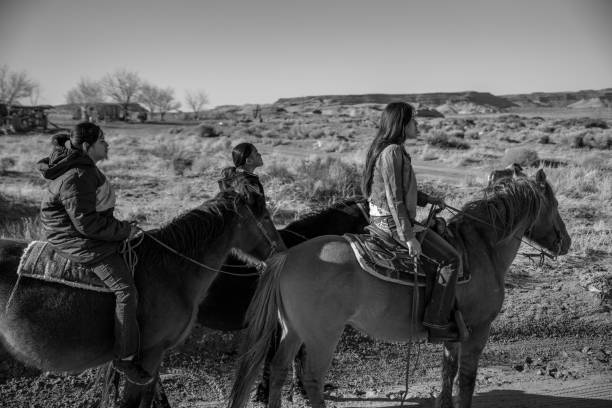 schwarz und weiß still fotografie von jungen navajo geschwister reiten ihre pferde - monument valley navajo mesa monument valley tribal park stock-fotos und bilder