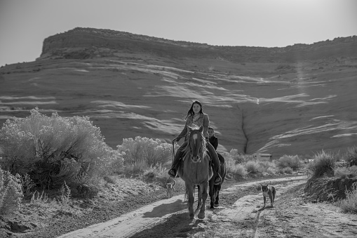A brother and his sisters riding their horses on their family's land on the Navajo reservation in Arizona, black and white photography