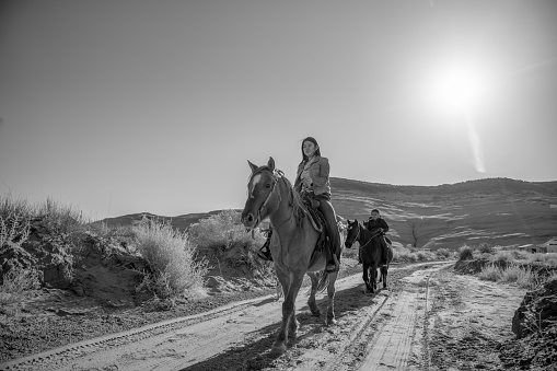 A brother and his sisters riding their horses on their family's land on the Navajo reservation in Arizona, black and white photography