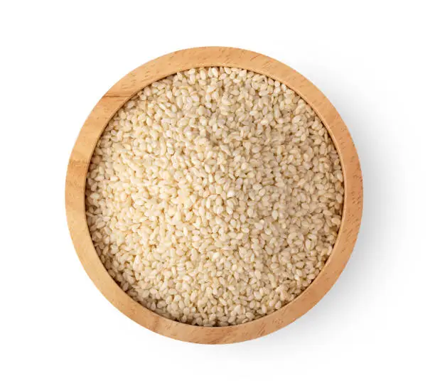 Sesame seeds in a woodenbowl isolated on white background