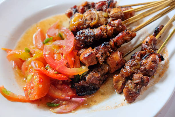 Close up Indonesian chicken satay skewer ready to eat, above white plate
