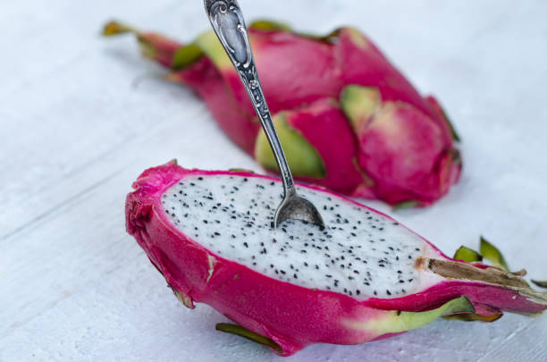 istock Two halves of dragon fruit with spoon on white background, tropical fruit 1215821599
