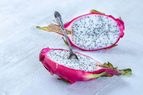 istock Two halves of dragon fruit with spoon on white background, tropical fruit 1215821601