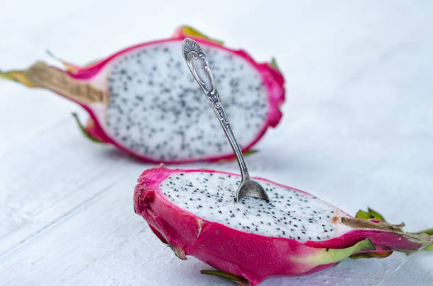 istock Two halves of dragon fruit with spoon on white background, tropical fruit 1215821611