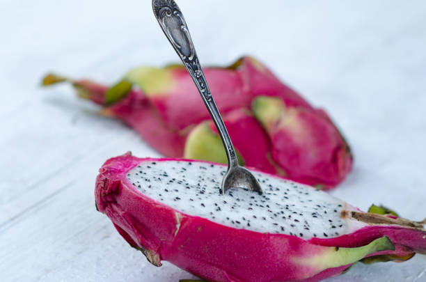 istock Two halves of dragon fruit with spoon on white background, tropical fruit 1215821612