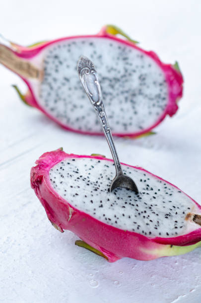 istock Two halves of dragon fruit with spoon on white background, tropical fruit 1215821614