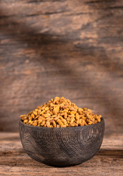 Fenugreek yellow seeds - Trigonella foenum-graecum. Organic fenugreek seeds in wooden bowl - Trigonella foenum - graecum fenugreek stock pictures, royalty-free photos & images