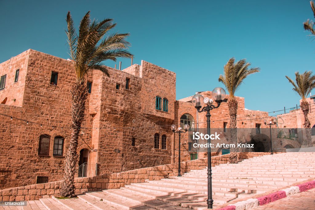 Israeli heritage sightseeing touristic site town Jaffa alley way with palms and stone buildings in summer time photography modern Instagram vintage toning style Old Stock Photo