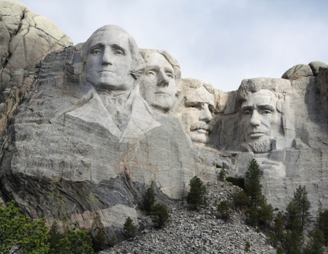 The four America's presidents, George Washington, Theodore Roosevelt, Thomas Jefferson and Abraham Lincoln, carved into the mountain at Mount Rushmore National Monument.  Showing the scree slope from the removed rock.