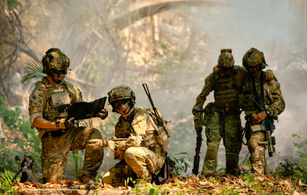 die armee hält an und diskutiert gemeinsam, bevor sie während der kämpfe im wald zum nächsten platz geht - militärisches trainingslager stock-fotos und bilder