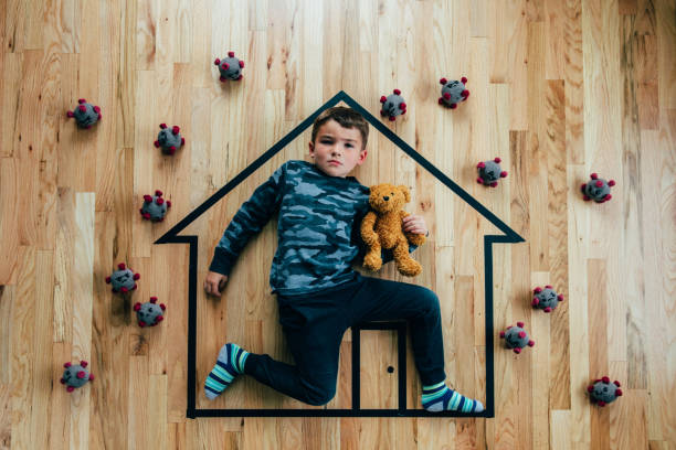 Stay Safe Stay Home A young boy with his teddy bear friend seeks protection from COVID-19, or the novel coronavirus, by sheltering in place in his home. He is ready to save his friends from the virus. emergency shelter photos stock pictures, royalty-free photos & images