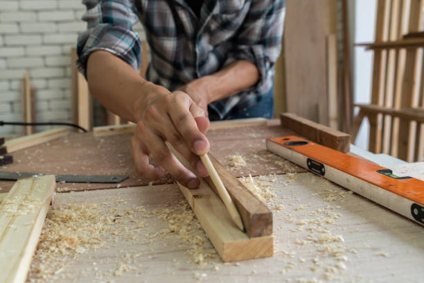 Carpenter working on wood craft at workshop to produce construction material or wooden furniture. The young Asian carpenter use professional tools for crafting. DIY maker and carpentry work concept. carpintero trabajando en la artesanía de madera en el taller para producir material de construcción o muebles de madera. el joven carpintero asiático utiliza herramientas profesionales para la elaboración. creador de bricolaje y concepto de trabajo de