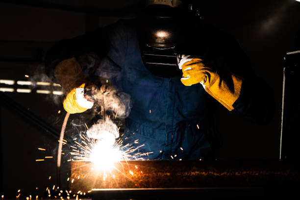 Metal welder working with arc welding machine to weld steel at factory while wearing safety equipment. Metalwork manufacturing and construction maintenance service by manual skill labor concept. soldadora metálica que trabaja con una máquina de soldadura por arco para soldar acero en fábrica mientras usa equipo de seguridad. servicio de fabricación de metalurtrabaja y mantenimiento de la construcción por concepto manual de mano de obra de hab