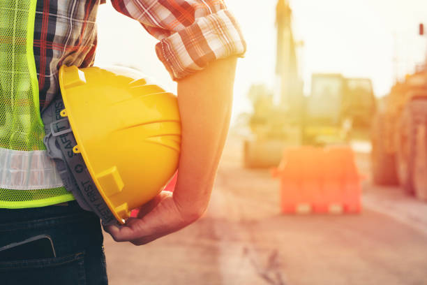 istock Engineer holding helmet at road construction site with machinery background,safety first concept 1215844007