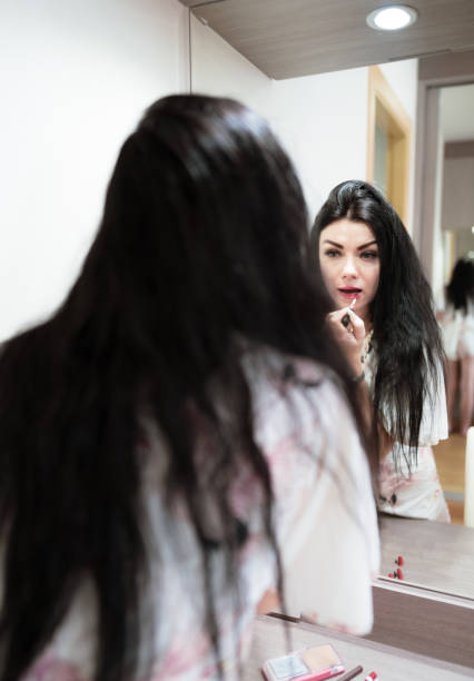 istock Beautiful woman getting dressed and using make-up in front of mirror in room 1215844032