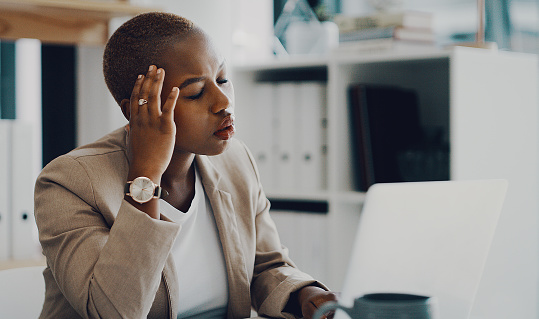 Shot of a young businesswoman looking stressed out while working on a laptop in an office