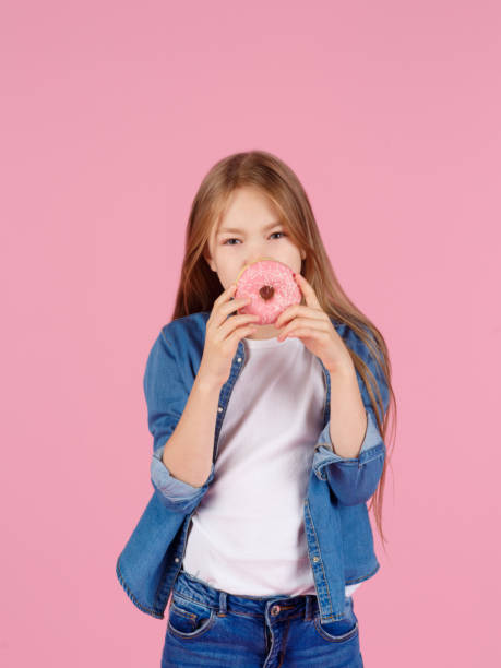 istock girl playing with a donut on a pink background 1215851807
