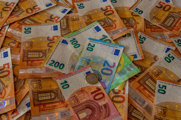 istock 1 coin of 10 and 20 euro notes with 50 notes in background 1215853773
