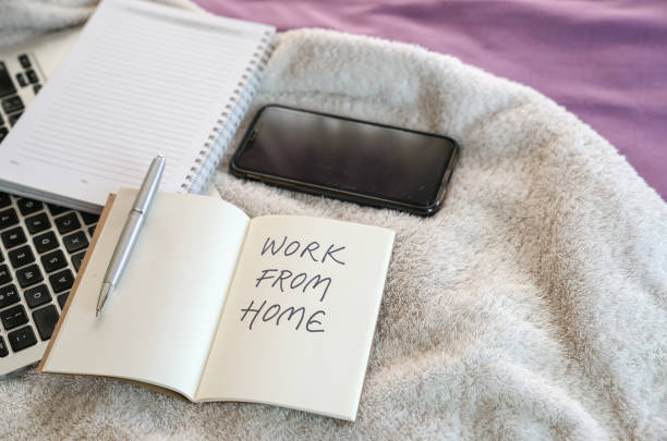 istock Work from home. Computer laptop, notepad and cellphone on top of bed. 1215854105
