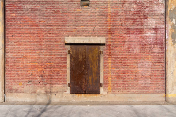istock Old weathered rusty factory gate and the dated brown brick wall 1215855302