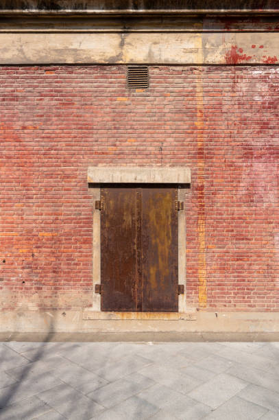 istock Old weathered rusty factory gate and the dated brown brick wall 1215855336