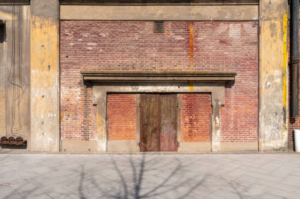 istock Old weathered rusty factory gate and the dated brown brick wall 1215855386