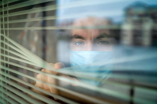 ウイルスの流行のために自宅で孤立している男 - blinds peeking looking window ストックフォトと画像