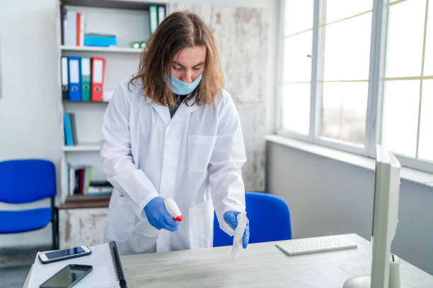 istock One man in protective gloves disinfecting office work space 1215856349