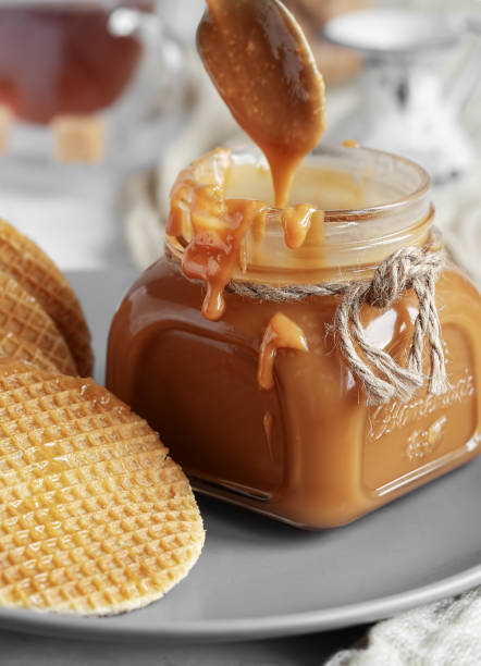 istock Spoon with tasty caramel sauce over jar on table. Selective Focus, Vertical Orientation. Close-up. 1215858581