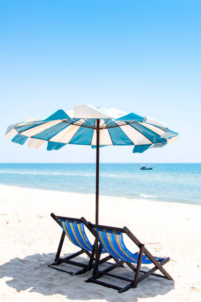 istock Two deckchair and umbrella facing out sea on idyllic beach 1215858696