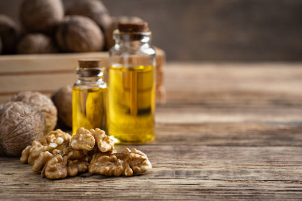 istock Glass bottle with walnut oil and walnut kernel on a wooden table. 1215859748