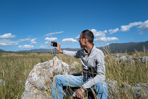 Asian men use mobile phones to take photos outdoors