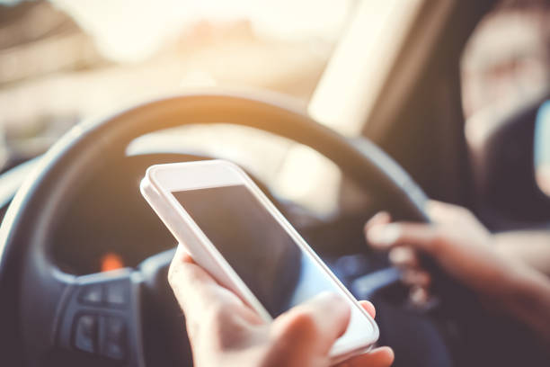 istock Hand of woman on steering wheel drive a car while using smartphone sunlight background. 1215864913